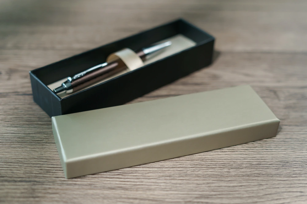 A pen in a gift box on brown wood table background